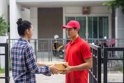 Man delivering package to female customer at gate