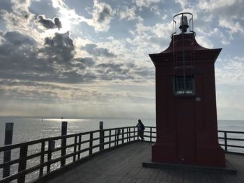 Lighthouse by sea against sky