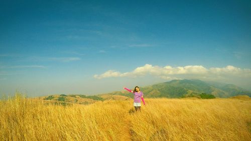 Full length of girl standing on field against sky