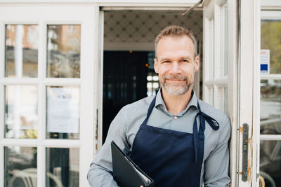 Portrait of restaurant owner standing by door