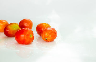 Close-up of wet tomatoes against white background