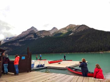 Rear view of people on lake against mountain range