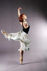 Ballet dancer dancing against gray background
