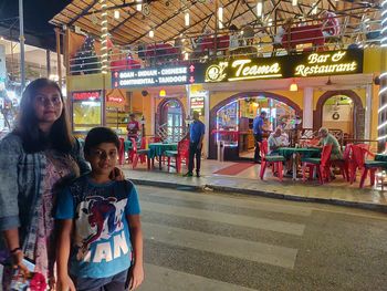 Rear view of people standing against illuminated wall