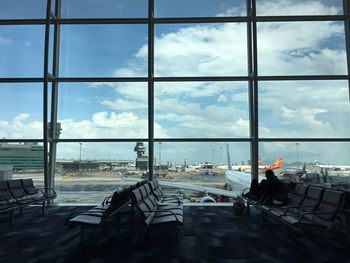 View of airport against cloudy sky seen through window