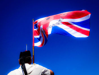 Low angle view of flag against clear blue sky