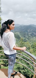 Side view of woman looking at mountains against sky