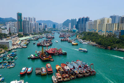 High angle view of boats in river by cityscape against sky