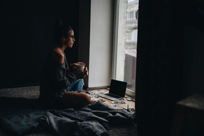 Side view of woman sitting at home