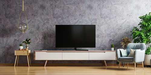 Led tv in living room the concrete wall with armchair,minimal design.3d rendering