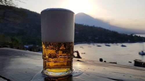 Close-up of beer glass on table against sky during sunset