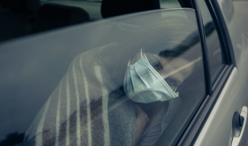 Woman wearing mask sitting in car