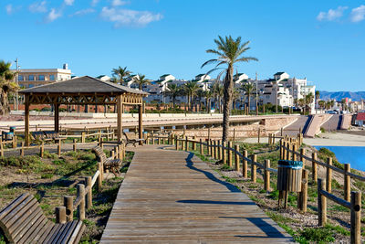 Walkway by sea against clear blue sky