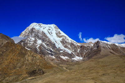 Scenic view of snowcapped mountains against blue sky