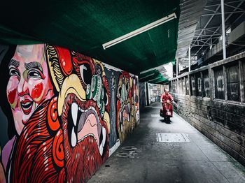 Rear view of man walking by graffiti in city