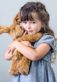 Portrait of girl holing stuffed toy against white background