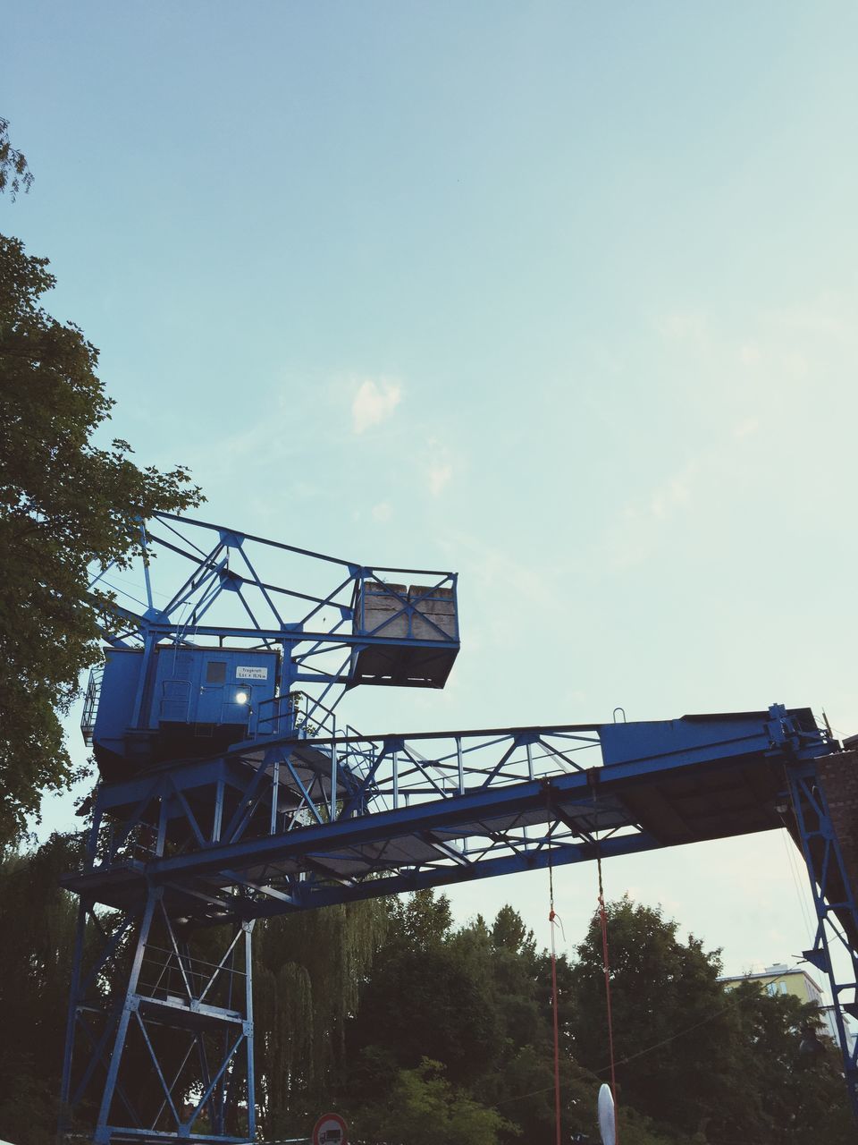 low angle view, built structure, architecture, sky, tree, building exterior, metal, day, outdoors, cloud - sky, metallic, no people, clear sky, construction site, cloud, blue, fuel and power generation, connection, industry, technology