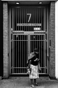 Rear view of woman walking by building in city