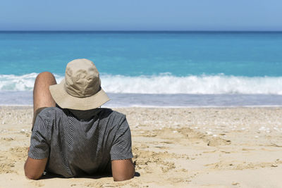 Rear view of woman sitting at beach