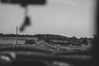 Road by landscape against sky seen through car windshield