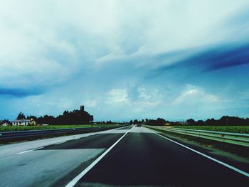 Empty road against cloudy sky