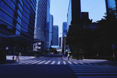 City street by modern buildings against sky