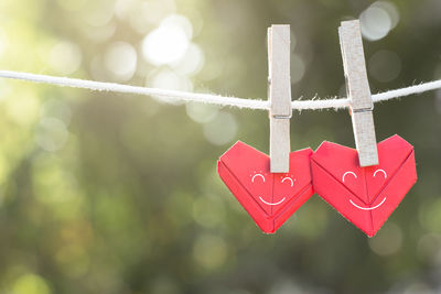 Close-up of red heart shape papers hanging on clothesline