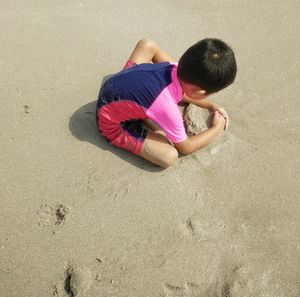 High angle view of boy playing on sand at beach
