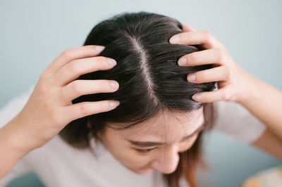 Close-up of woman showing hair with hands against wall