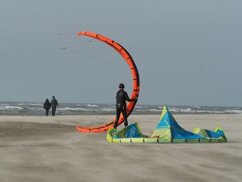 Rear view of man preparing kiteboard at beach