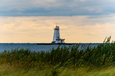 Lighthouse by sea against sky