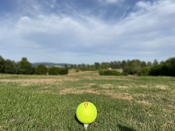 Golf ball on field against sky