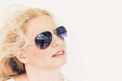 Portrait of young woman wearing sunglasses against white background