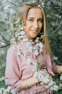 Blonde girl on a spring walk in the garden with cherry blossoms. female portrait, close-up. 