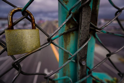 Close-up of padlock hanging on chainlink fence