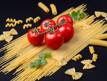 High angle view of tomatoes with pasta on black background