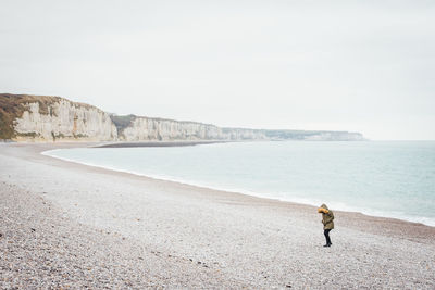 Rear view of man on beach against clear sky