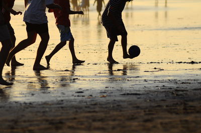 Low section of boys playing on sand at beach