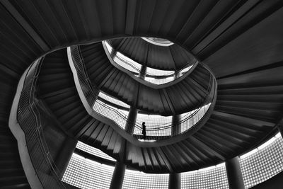 Low angle view of silhouette woman standing on spiral staircase