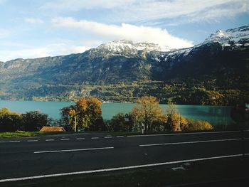 Road by trees and mountains against sky