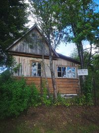 Exterior of abandoned house and trees against sky