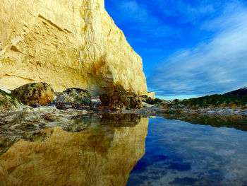 Rock formations by sea against blue sky