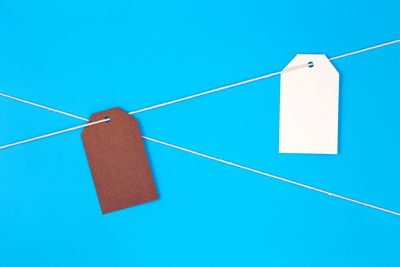 Papers hanging on rope against blue background