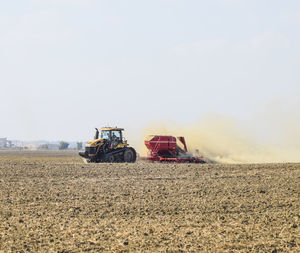 Tractor on agricultural field against clear sky