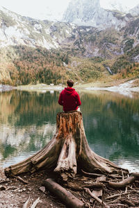 Rear view of man looking at lake against mountain