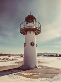 Lighthouse on beach against sky