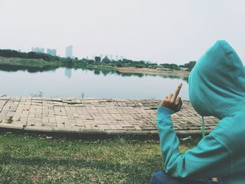 Man showing middle finger by lake