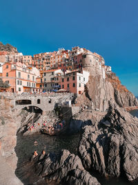 Buildings by rocks against blue sky