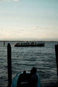 Rear view of man on boat in sea against sky