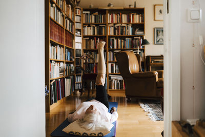 Elderly woman doing leg-up exercise in living room